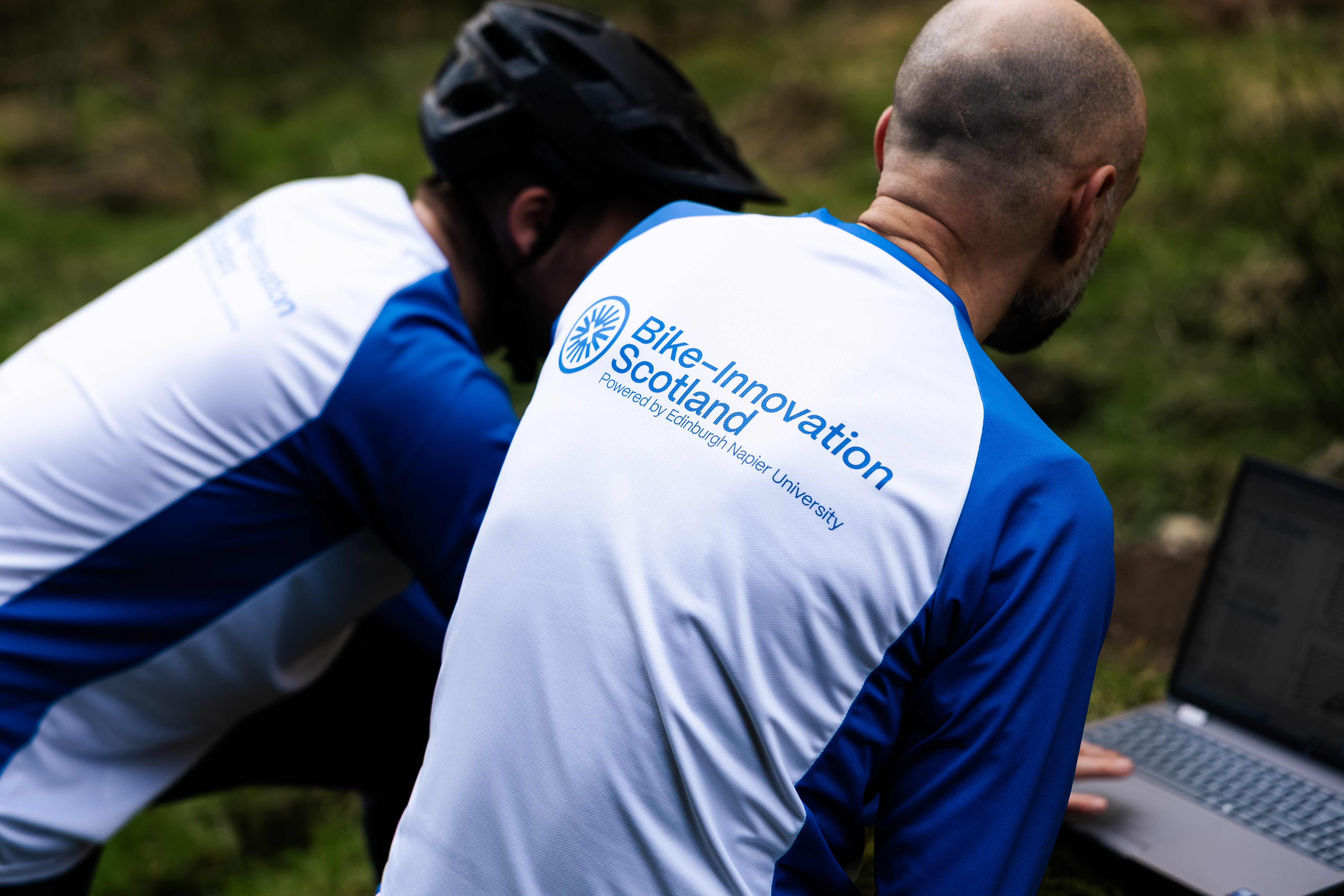 Back of two people in Bike Innovation Scotland tops