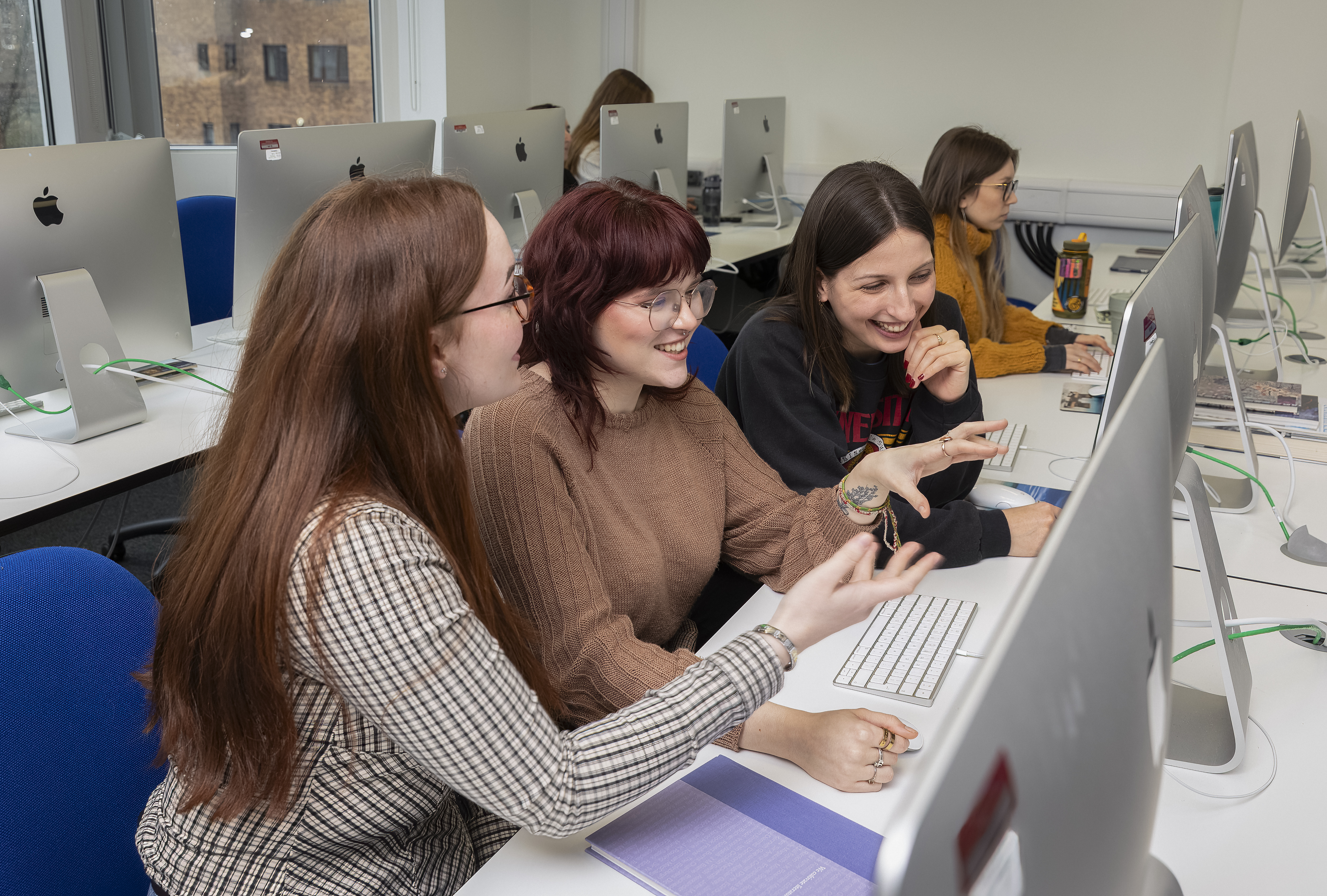 People working at their desks, smailing and looking at their screens