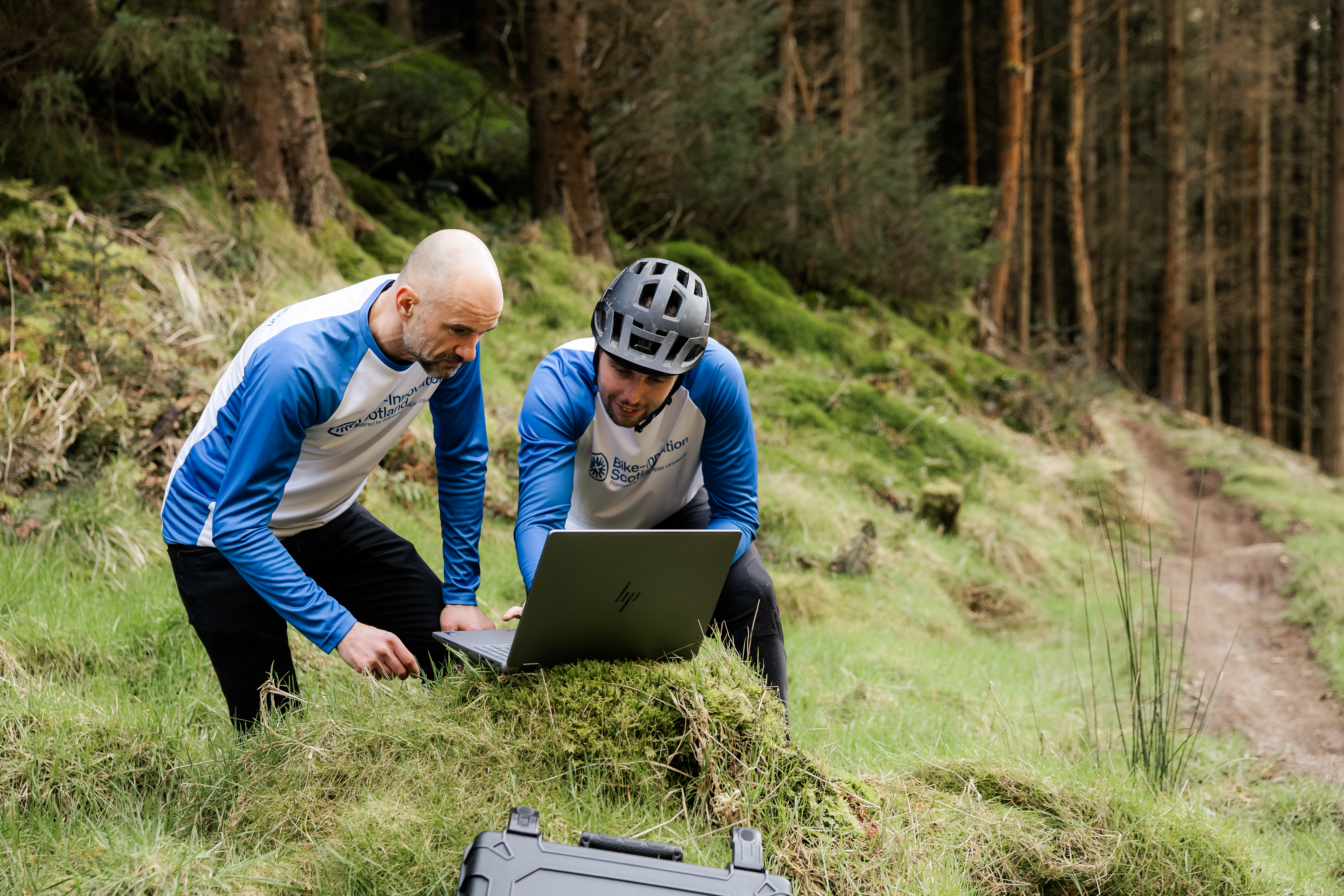 Two people looking at their screen in the forest